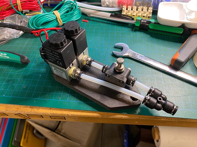 3D printed bracket holding two air valves and a flow restrictor, splitting from and then combined into one hose by two Y adaptors